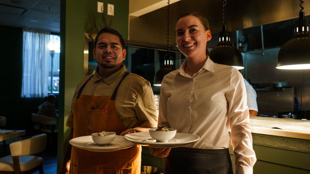 Chef Ivan with a server holding plates at Flour & Time restaurant.