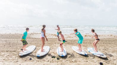 An instructor coaches five children on how to surf on the Port Aransas Beach.