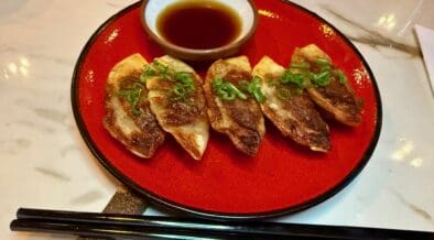 Tiki Taka's Gyoza on a plate next to chopsticks with a small bowl ofsherry dip.