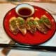 Tiki Taka's Gyoza on a plate next to chopsticks with a small bowl ofsherry dip.