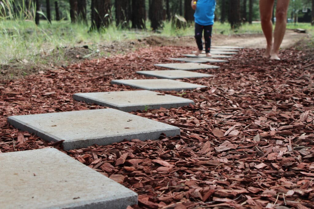 A toddler and mother walk barefoot on cement diamonds on Flagstaff's Barefoot Trail.