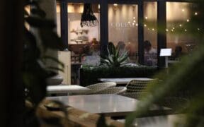 COURSE Restaurant Patio with outdoor seating and an expansive window showing the interior of the restaurant,