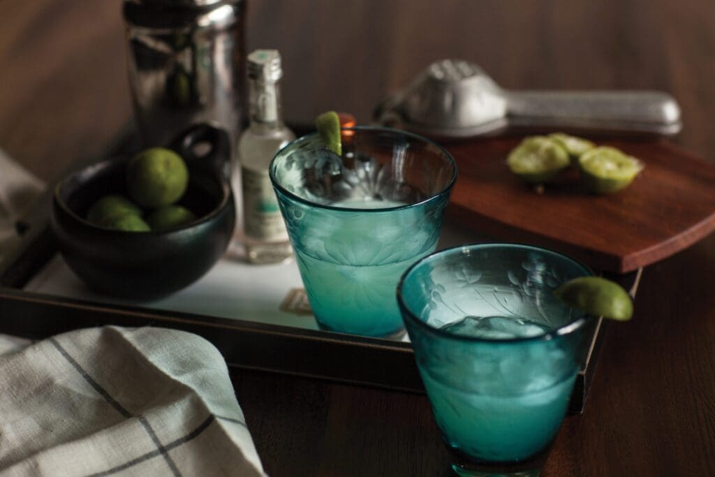 Two cocktail glasses are on a tray with limes and a muddler at The Hotel Emma in San Antonio.