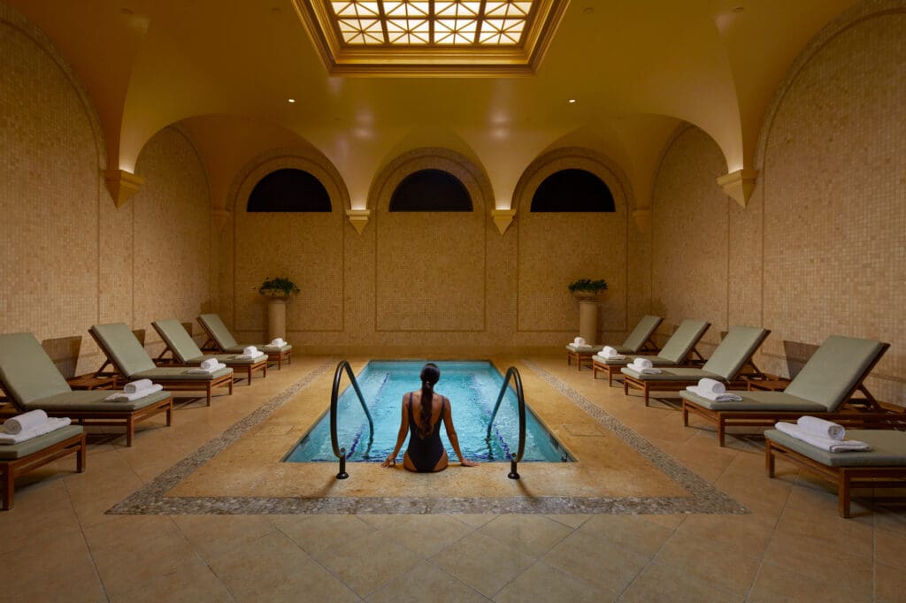 A woman sits at the edge of a spa pool at The Spa Pelican Hilton.