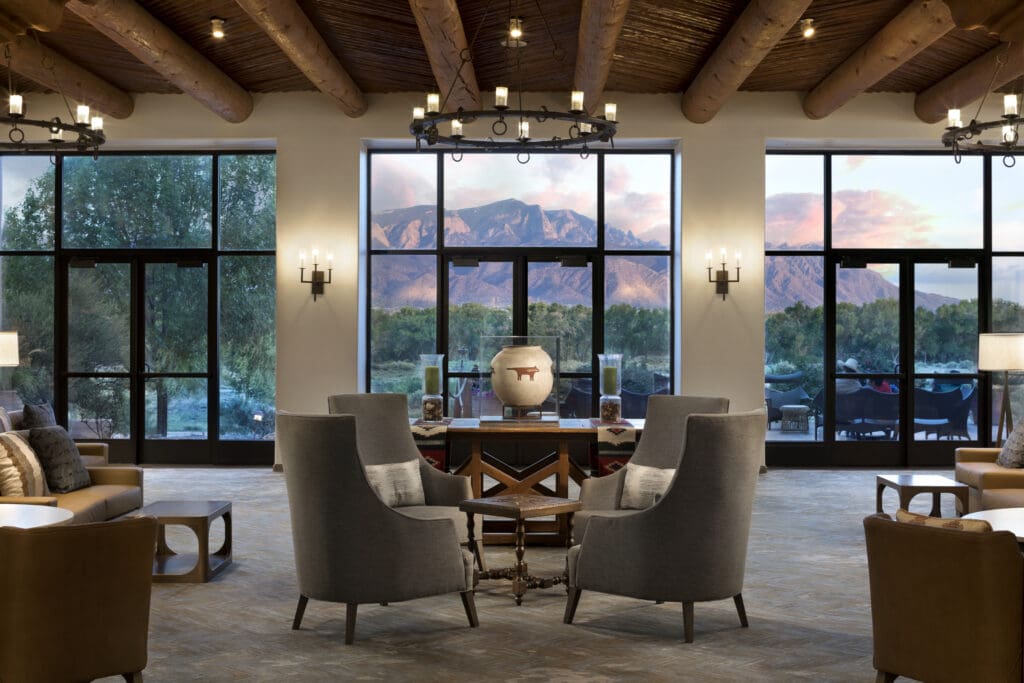 The living room of the Hyatt Regency Tamaya with tables and chairs and views of New Mexico mountains.