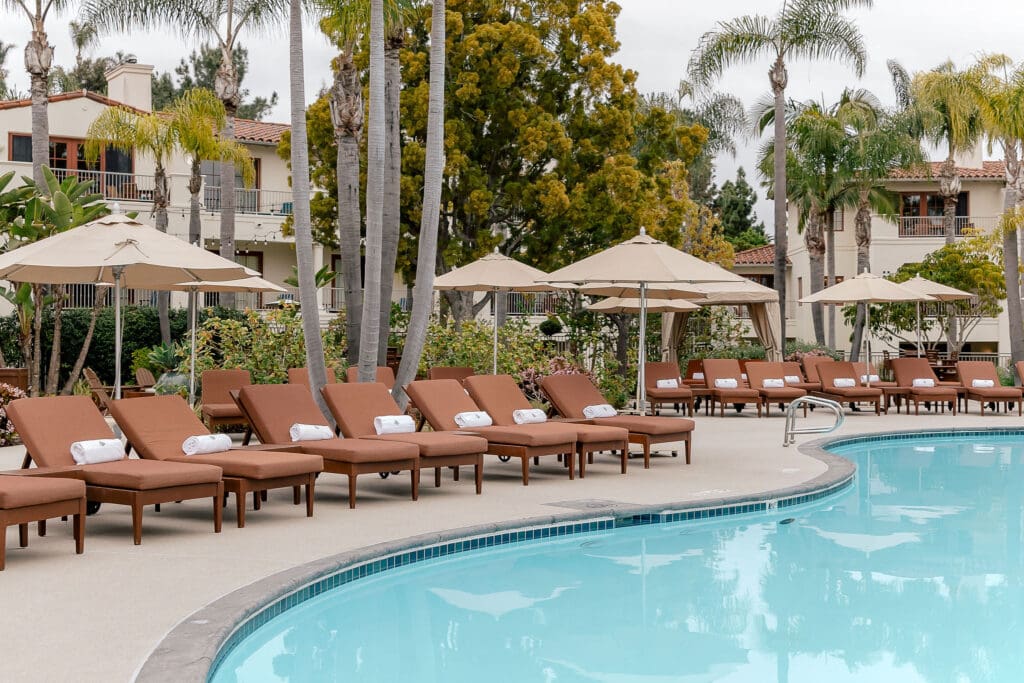 One of two Four Seasons Residence Club Aviaral pools with poolside lounge chairs and towels covered by umbrellas.