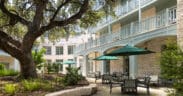 The Springhouse Cafe with outdoor umbrellas outside of the Hyatt Regency Hill Country Resort with large tree and landscaping