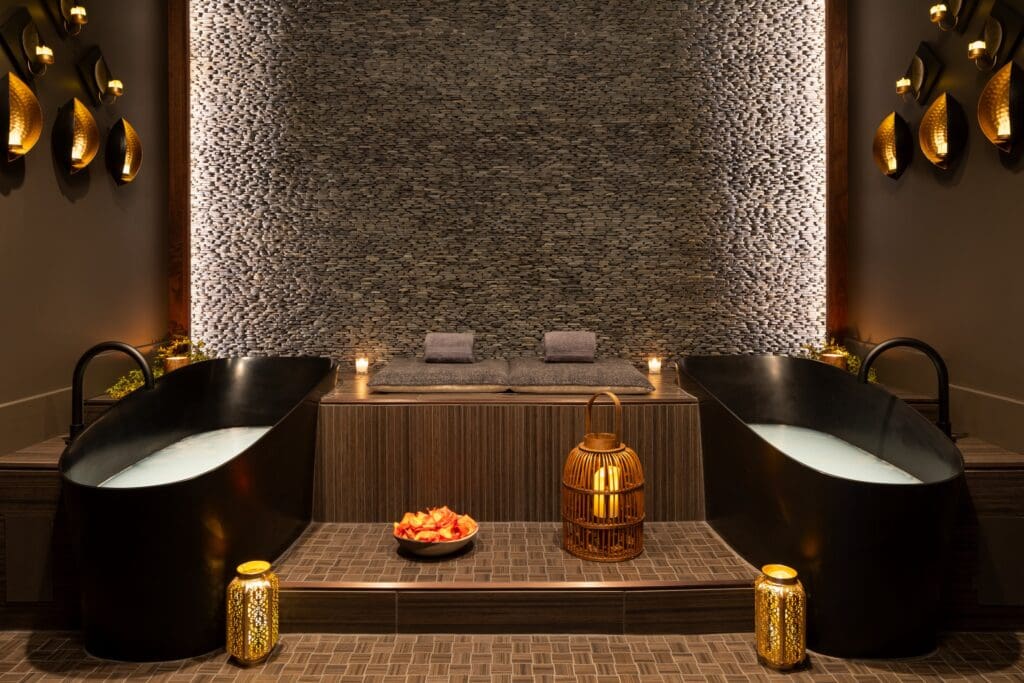 Two filled copper bathtubs are separated by a pillow-top bench and decorative lanterns in Ambiente's Velvet Spa.