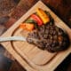 A Tomahawk steak and peppers on a cutting board at J&G Steakhouse at The Phoenician