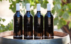 Four D.A. Ranch wine bottles atop a wine barrel as part of the ranch's Arizona Wine Club.