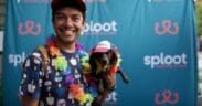 An ally of LGBTQIA+ wearing a rainbow lay holds a dachshund with matching lay for Denver's Paws with Pride event.