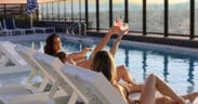 Two women in Adorandak chairs toast each other with cocktails on the Rose & Thorn restaurant atop the Penrose.
