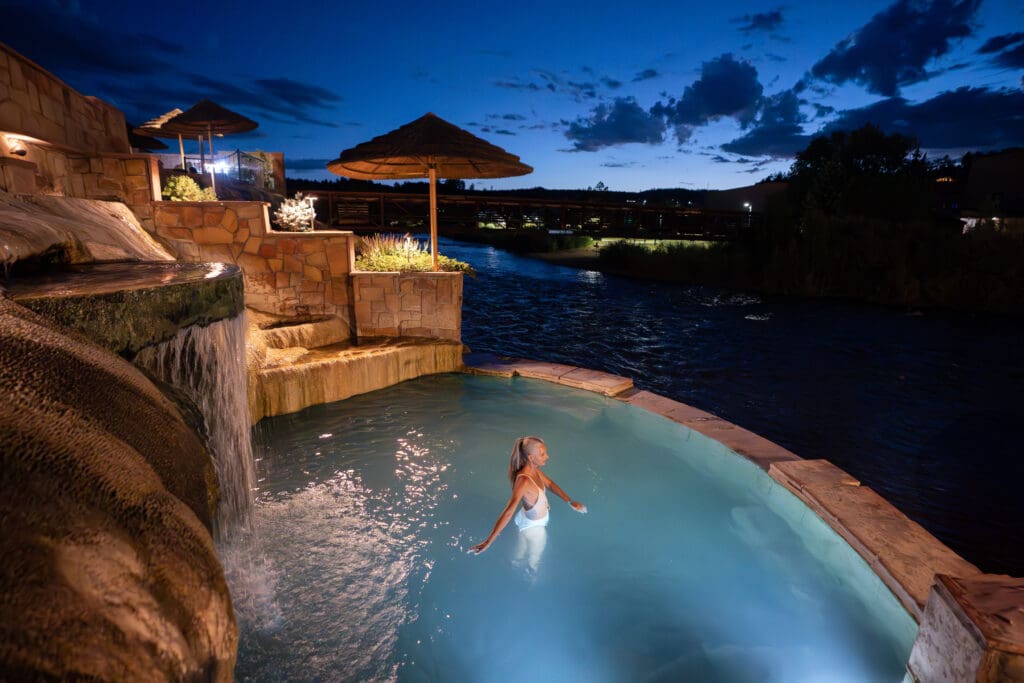 A woman enjoying one of The Springs Resort's many geothermal plunge pools at night.