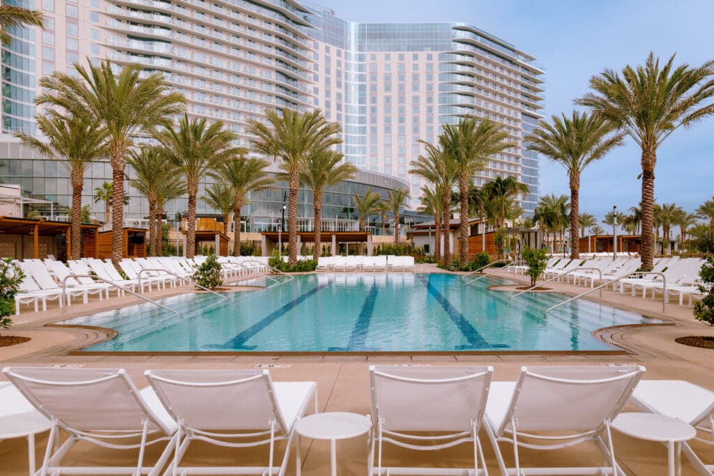 A large pool surrounded by the Gaylord Pacific Resort in Chula Vista, flanked by lounge chairs and cabanas.