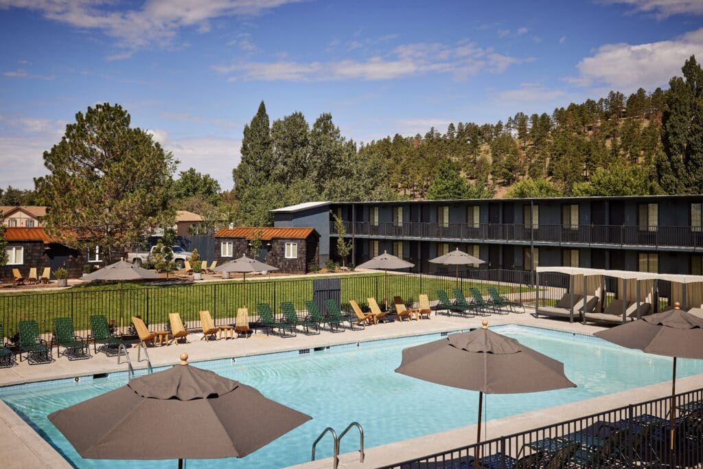 A rectangular pool with cabanas and umbrellas in the courtyard of the High Country Motor Lodge in Flagstaff.
