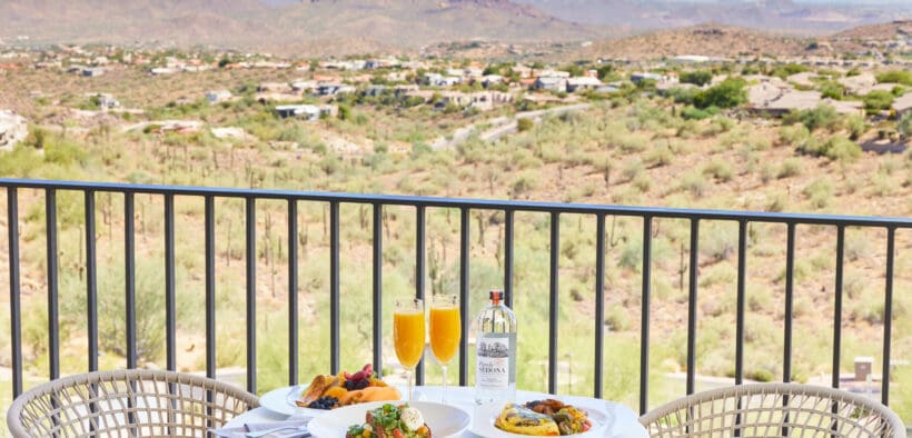 Three plates of food and two mimosa glasses on an outdoor table at CIELO at ADERO Scottsdale.