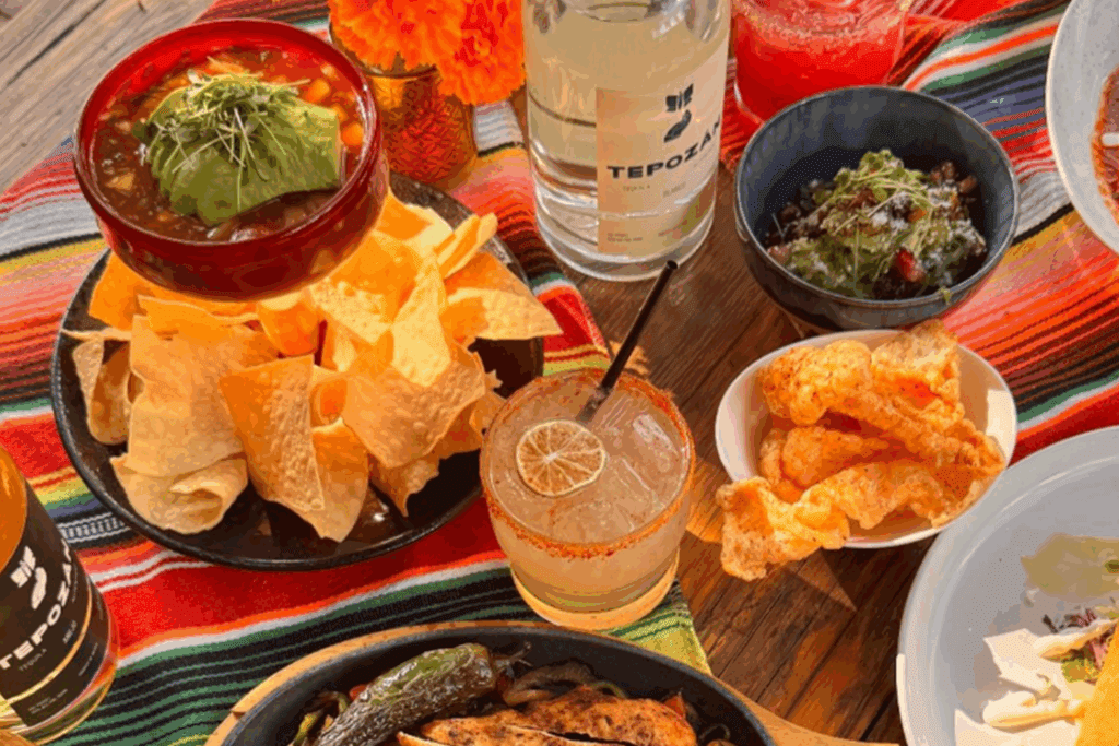 Several plates of Mexican food with chips, guac and margaritas at Recreo Cantina Chandler.