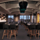 Intimate dining tables with modern chairs and dynamic overhead light installations fill Sparrow restaurant.