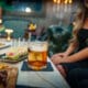 A woman sits in front of a plate of appetizers and a cocktail at The Peacock at DC Ranch speakeasy.