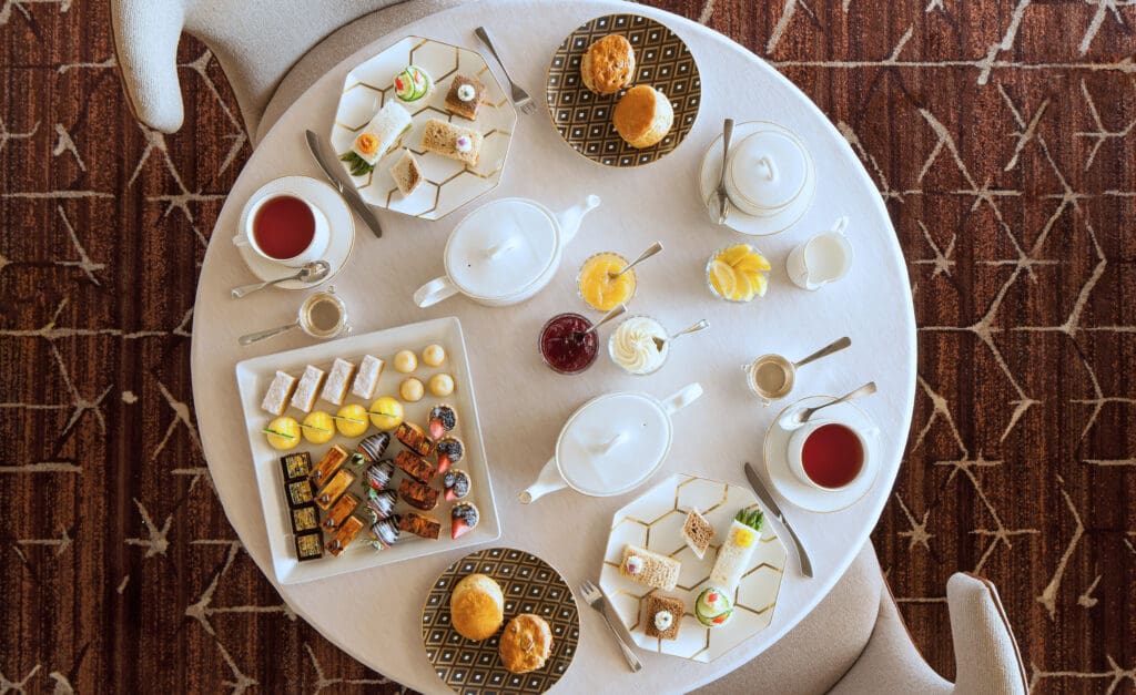 An Afternoon Tea table setting at The Phoenician with tea pots, finger sweets, teacups and biscuits.