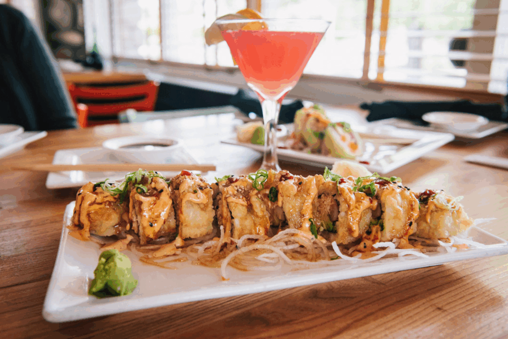 A sushi roll with wasabi and a cocktail on a table at Sushi Brokers Arcadia.