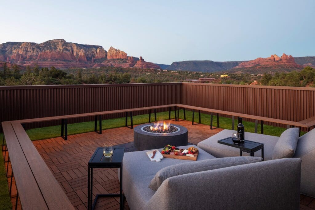 Rooftop of Ambiente Sedona atrium with firepit, two comfy sofa loungers a charcuterie tray and wine overlooking Sedona Red Rocks.