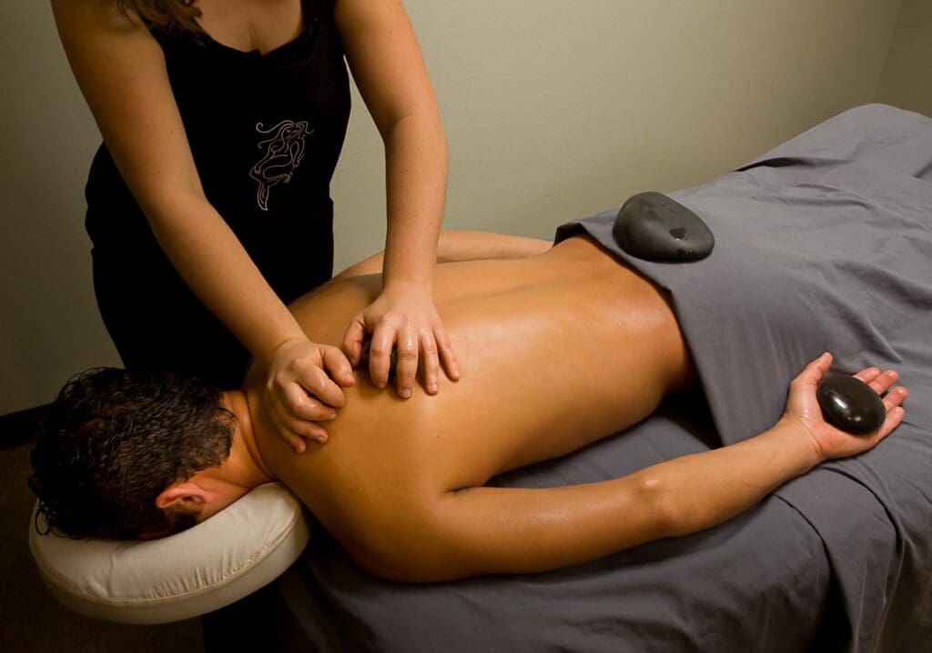 A man receives a hot stone massage from a female massage therapist at Betty's Bath & Day Spa.