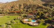 An aerial view of Castle Hot Springs Resort with main lodging and pool set near the mountains.