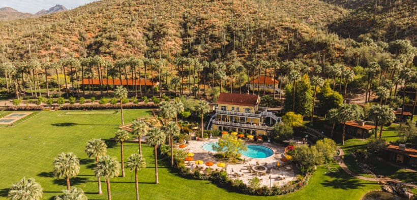 An aerial view of Castle Hot Springs Resort with main lodging and pool set near the mountains.