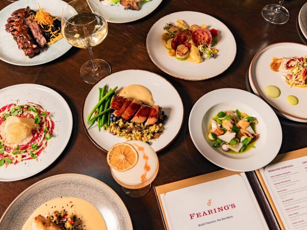 Several Southwestern dishes elegantly plated at Fearing's in The Ritz-Carlton Dallas with a menu on the table.