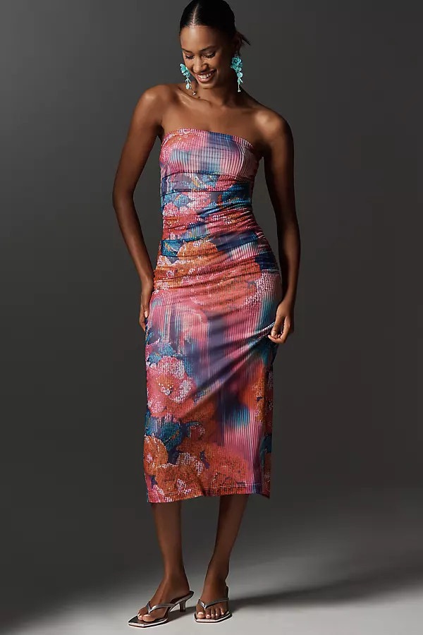 A woman wears a form-fitting Soleil Slim Strapless Ruched Mesh Dress with kitten heels and big turquoise earings.