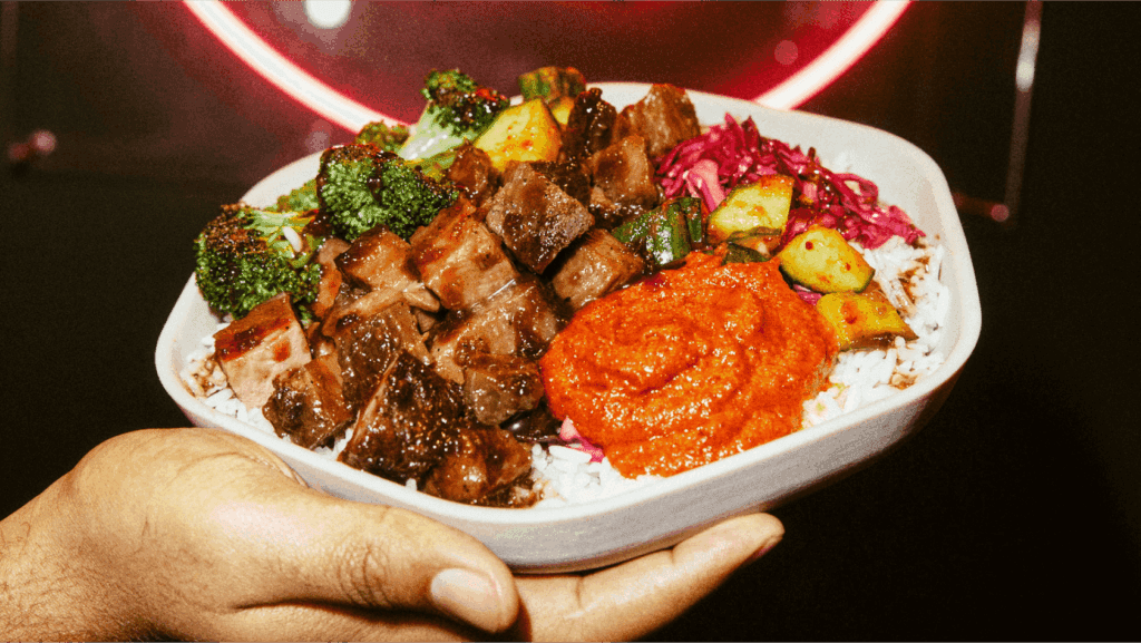 A person's hand holds a Korean BBQ Bowl from Sweetgreens with meat, broccoli and rice, locations opening locations in Phoenix and Scottsdale. 