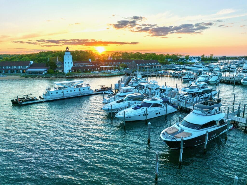 Montauk Yacht Club with resort property, dock and docked yachts with a sunset background. 