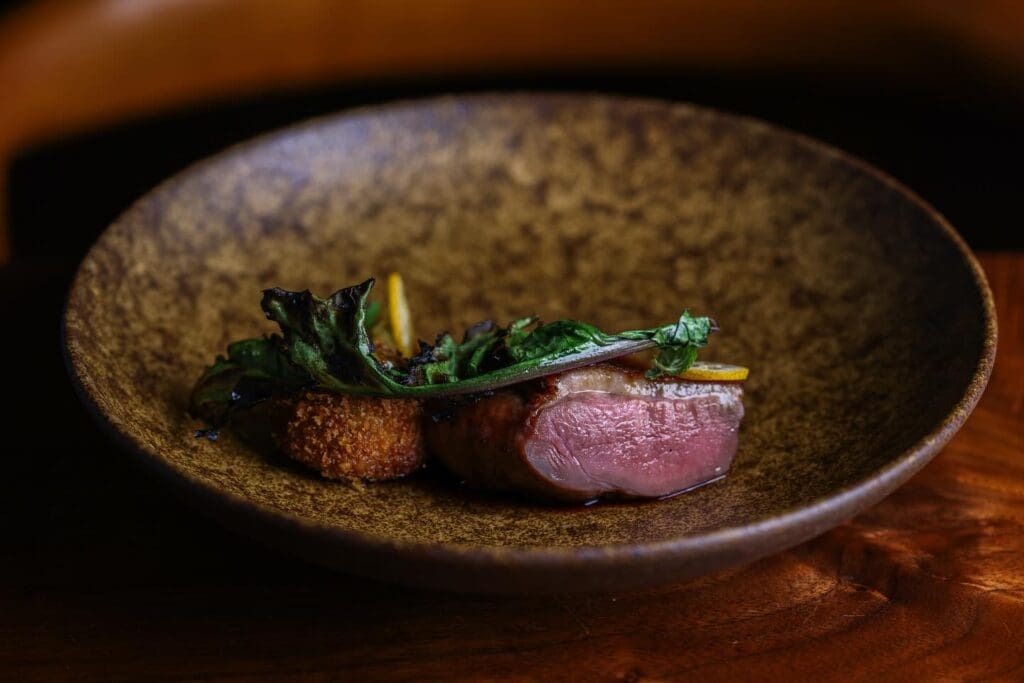 A filet and crab cake surf and turf dish in a decorative, modern bowl at Matsu in Oceanside, California.