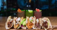 A plate of different types of tacos at Salt + Lime Modern Mexican Grill in Arcadia with three cocktails in the background.