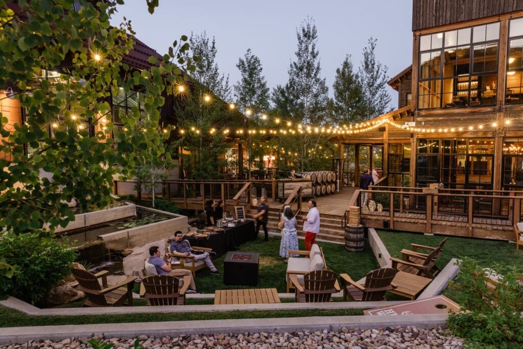 The Nelson Cottage by High West Distillery outdoors with people gathered near the firepit, under fairy lights. 