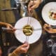 Group of people sharing Chinese steamed dumpling, view of the table with four hands holding chopsticks on fusion food luxury restaurant.