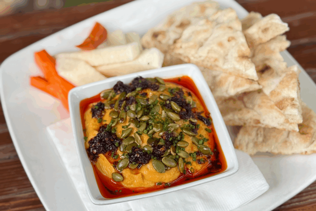 A plate with pitas and veggies next to a dipping bowl with pumpkin hummus from 32 Shea in Scottsdale.