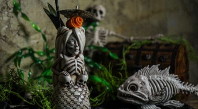 A spooky skeletal mermaid drink holder next to a skeletal fish at a Black Lagoon Pop-up.