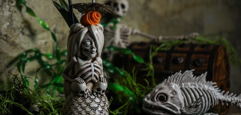 A spooky skeletal mermaid drink holder next to a skeletal fish at a Black Lagoon Pop-up.