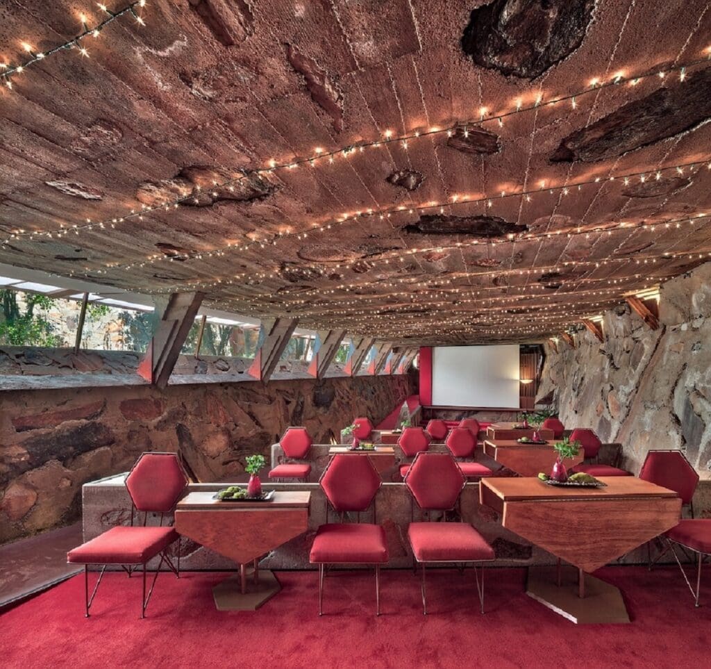 Frank Lloyd Wright's Taliesen West Cabaret Theater with red carpet, seating, side tables and movie screen.