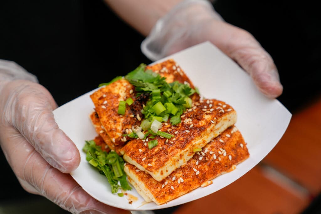 A person wearing food-service gloves holds a plate of Asian food from the Panda Fest in Phoenix.