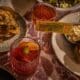Cocktails and French-American inspired dishes are decoratively placed on a table at Society Swan in Scottsdale.