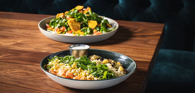 Weekend at Bernie's Salad and The G.O.A.T. Salad on a wood table booth at Sparrow restaurant in Peoria.