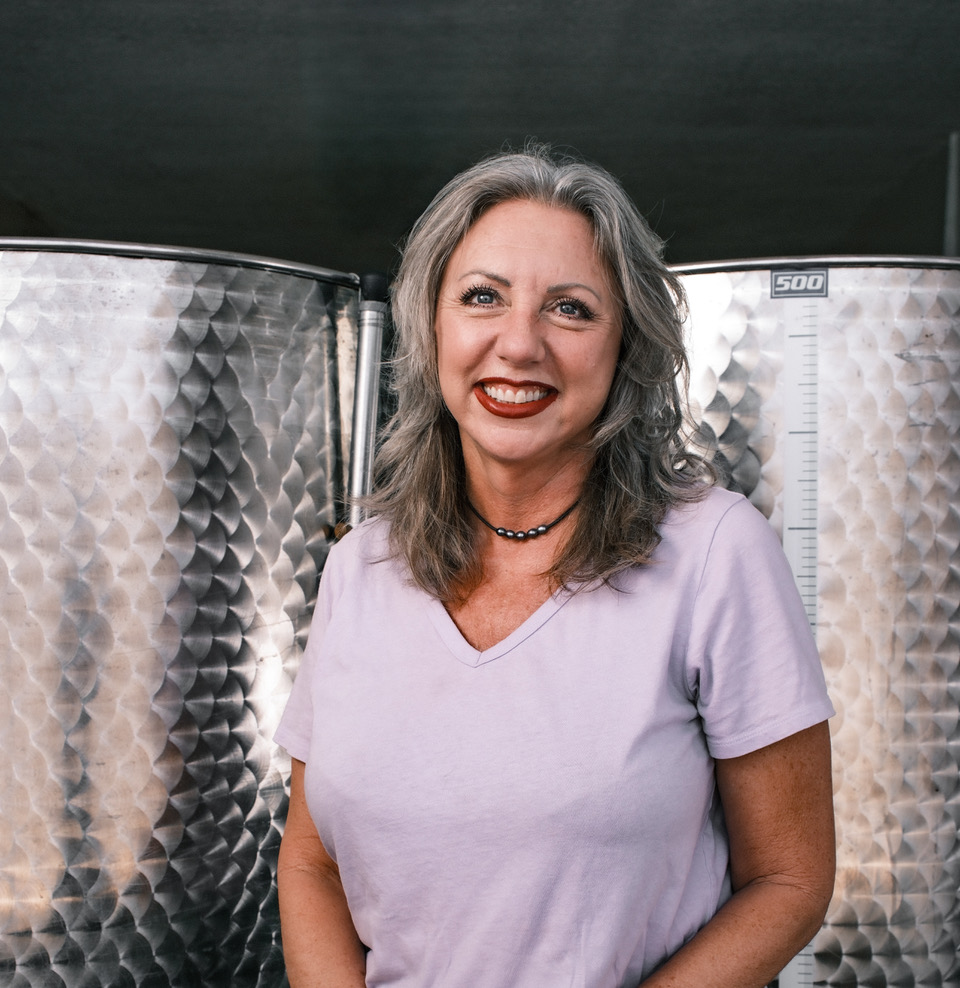 Suzette Smith, founder of Garden Goddess Ferments, with two fermentation vats in the background.