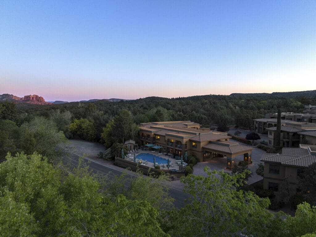 The Mountain Modern Sedona hotel with outdoor pool and hot tub, surrounding by trees and Red Rocks in the distance.