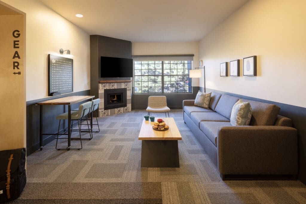 A Modern Mountain Sedona suite with a couch, coffee table, fireplace and desk with two chairs. 