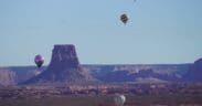 Three hot air balloons in various positions in the sky in Page, Arizona, for the annual Balloon Regatta.