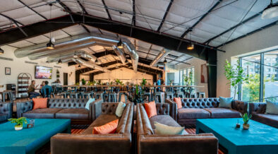 Formation Brewing with turquoise tables, couches and booths with plants and large windows.
