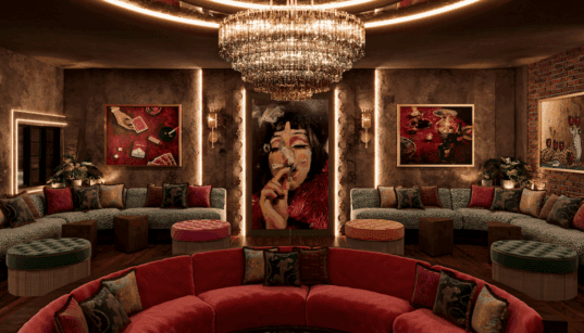 A velvet red circular couch below a stunning chandelier with forest green velvet half circle couches and Mexican-inspired decor at Pablo's Downtown Phoenix.